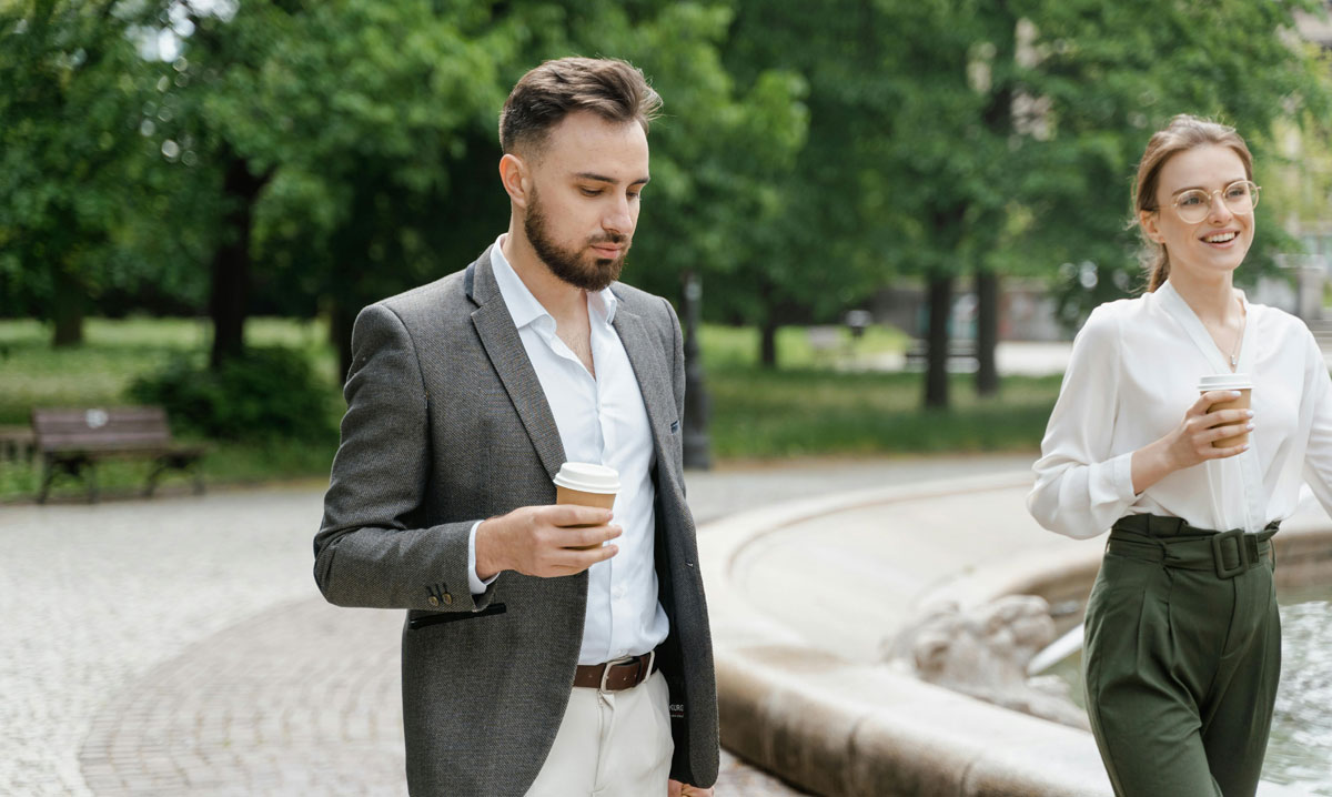 para w parku warszawskim spaceruje z kawa w ręku